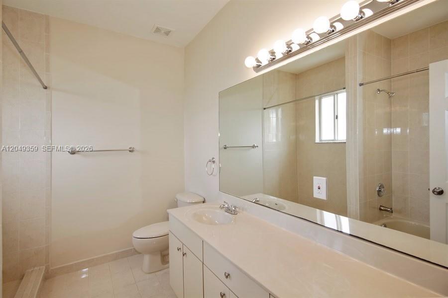 A bathroom features a white vanity, a large mirror, a toilet, and a shower-tub combination — HOMESTEAD, FL