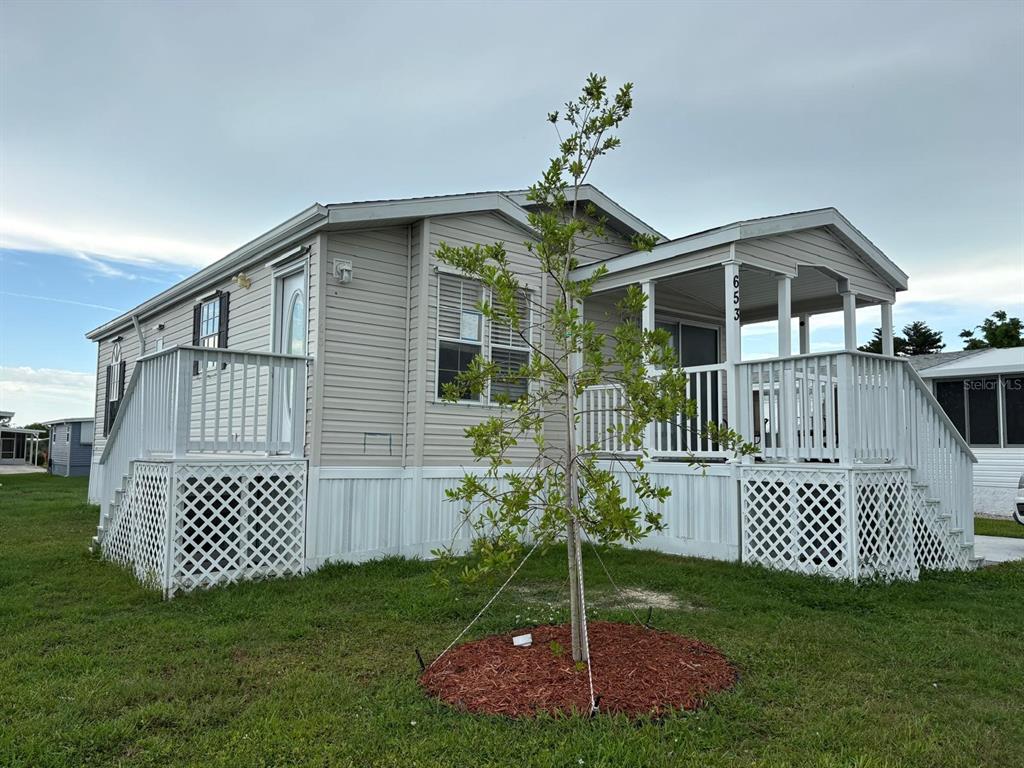 A mobile home exterior features a covered front porch with white railings and stairs — 653 LOS ALTOS, NORTH PORT, FL