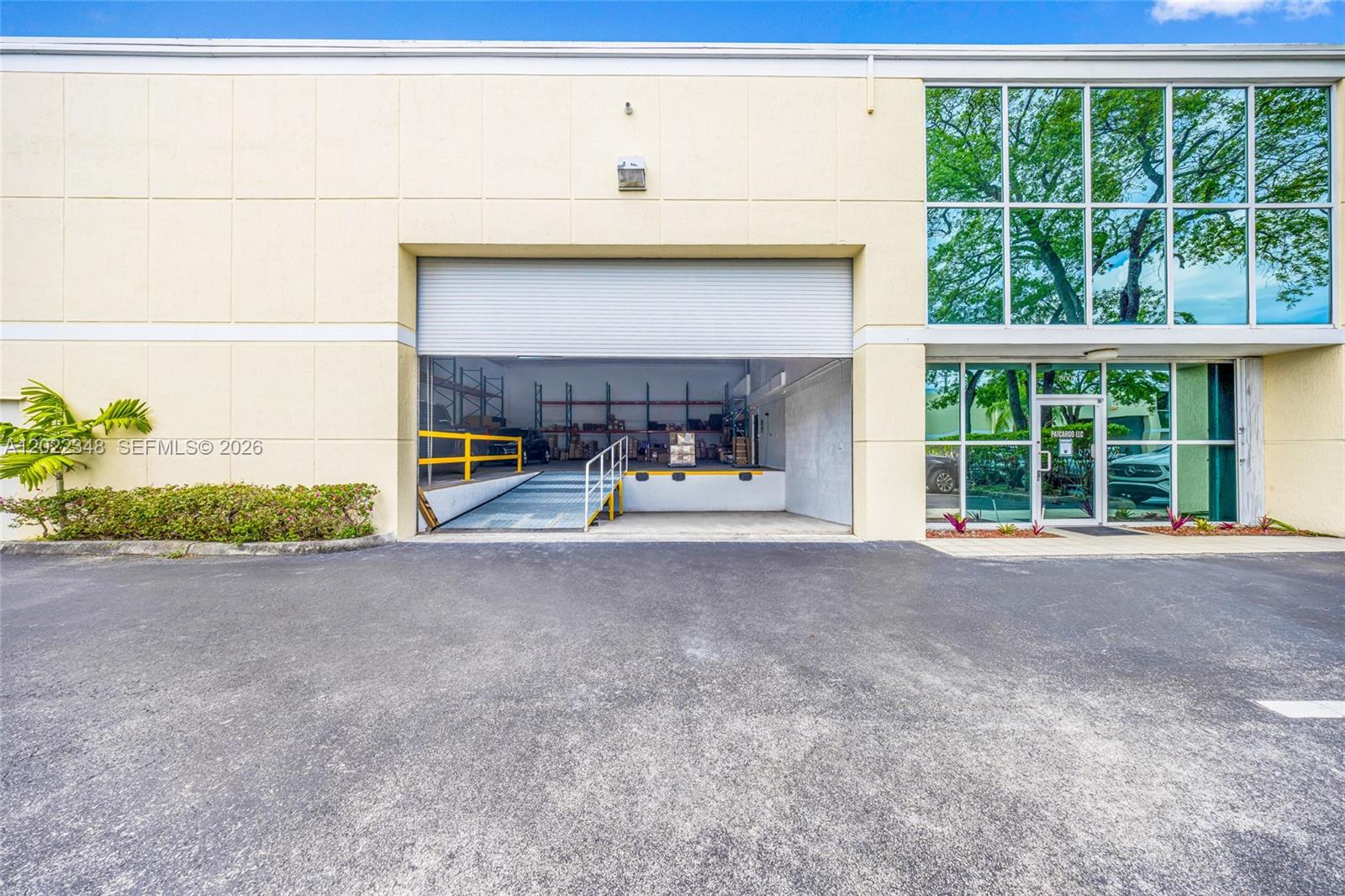 An exterior view of a warehouse building featuring a loading dock and glass storefront — 8009 NW 29th St # 8009, Doral FL 33122, DORAL, FL
