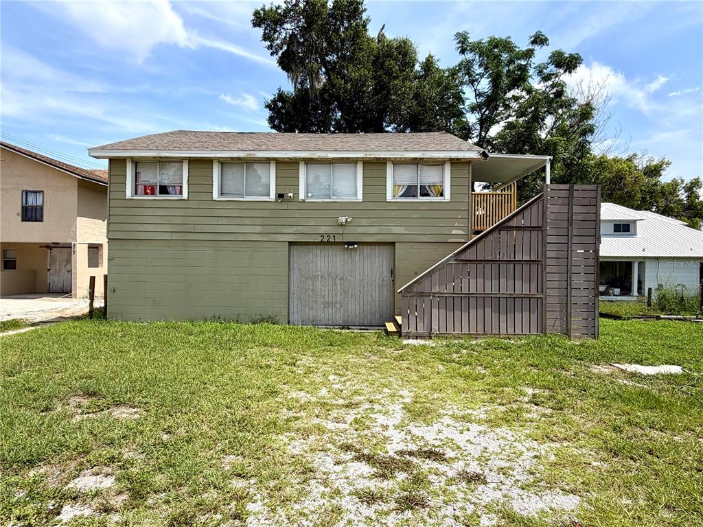 A two-story house with green siding, a ground-level garage, and an exterior wooden staircase — 221 AVENUE C NE, WINTER HAVEN, FL