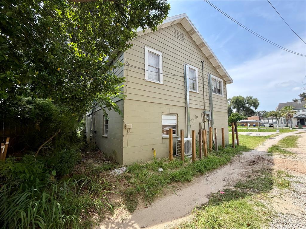 The exterior side view of a two-story house features tan siding, block walls, and windows — 221 AVENUE C NE, WINTER HAVEN, FL
