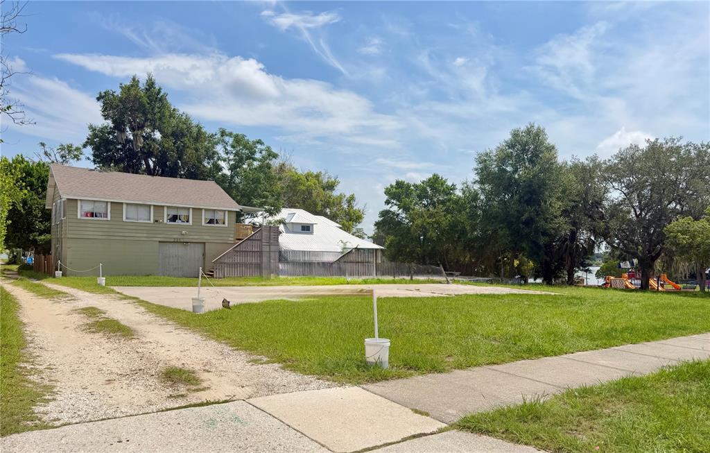 A two-story house with a large concrete driveway and a grassy yard under a blue sky — 221 AVENUE C NE, WINTER HAVEN, FL