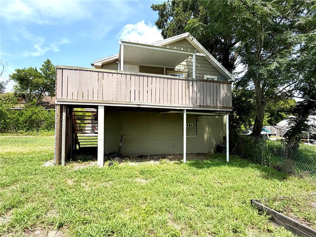 A two-story house features a large wooden deck with stairs leading to the backyard — 221 AVENUE C NE, WINTER HAVEN, FL