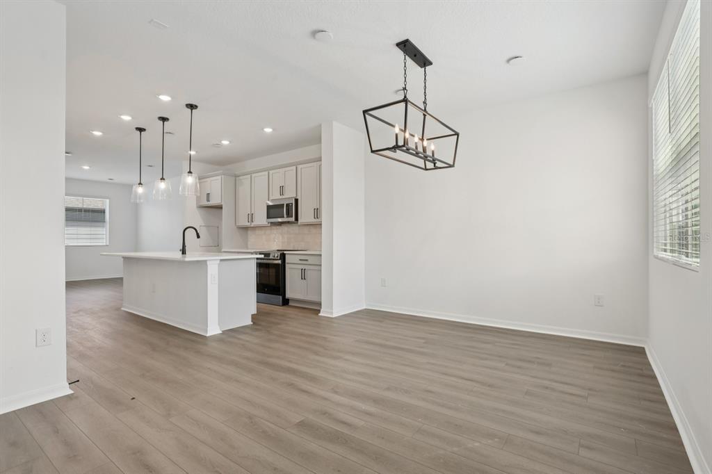 A modern kitchen with white cabinets and an island opens to a dining area — 17398 SWEET MORO DRIVE, WINTER GARDEN, FL