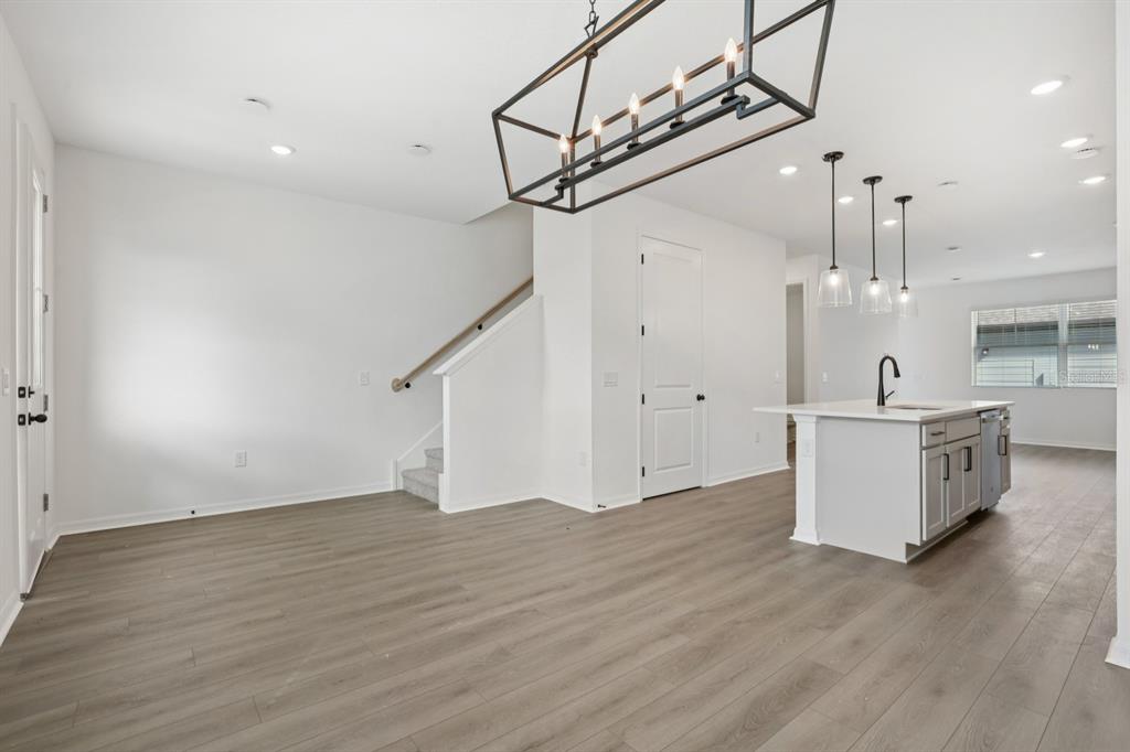 An open-concept kitchen and dining area features light wood flooring, white cabinetry, and pendant lighting — 17398 SWEET MORO DRIVE, WINTER GARDEN, FL
