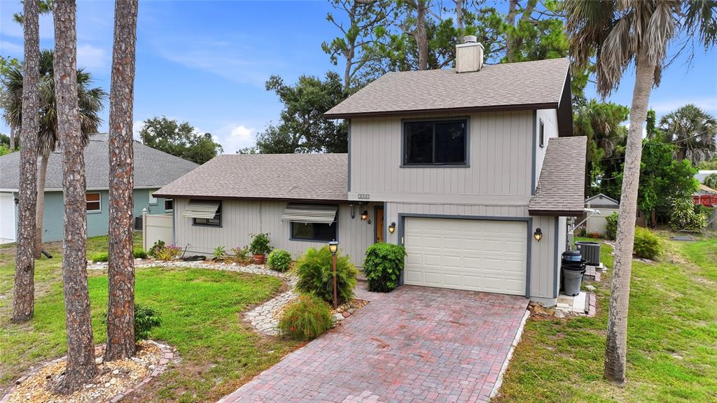 A two-story house with light gray vertical siding, a brick driveway, and a shingled roof — 2631 FIESTA DRIVE, VENICE, FL