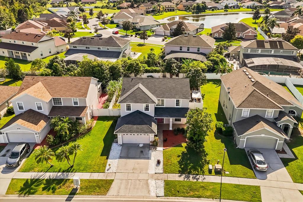 An aerial view shows three suburban houses with driveways and lawns in a residential neighborhood — 2530 BAYKAL DRIVE, KISSIMMEE, FL