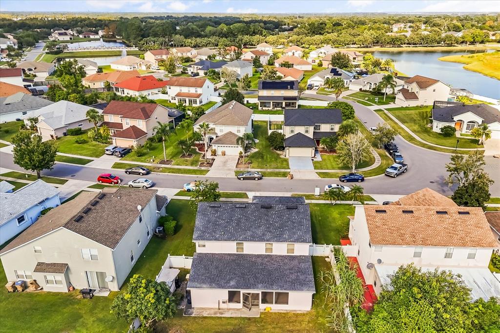 An aerial view shows a suburban neighborhood with multiple single-family homes and a nearby lake — 2530 BAYKAL DRIVE, KISSIMMEE, FL