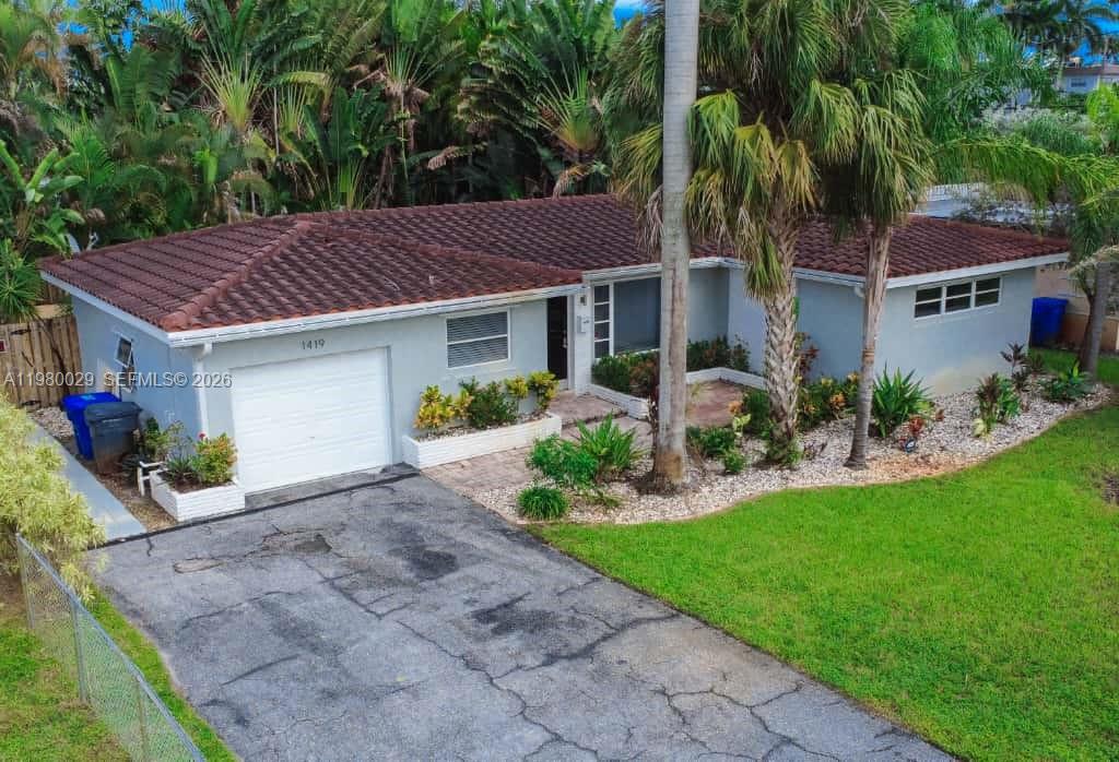 An exterior view of a single-story house with a tiled roof, garage, and paved driveway — 1419 N 16th Ct, Hollywood FL 33020, HOLLYWOOD, FL