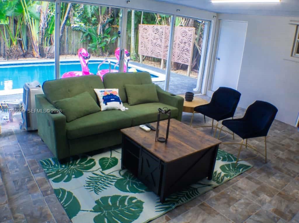 A living room features a green sofa, a wooden coffee table, and a pool view — 1419 N 16th Ct, Hollywood FL 33020, HOLLYWOOD, FL