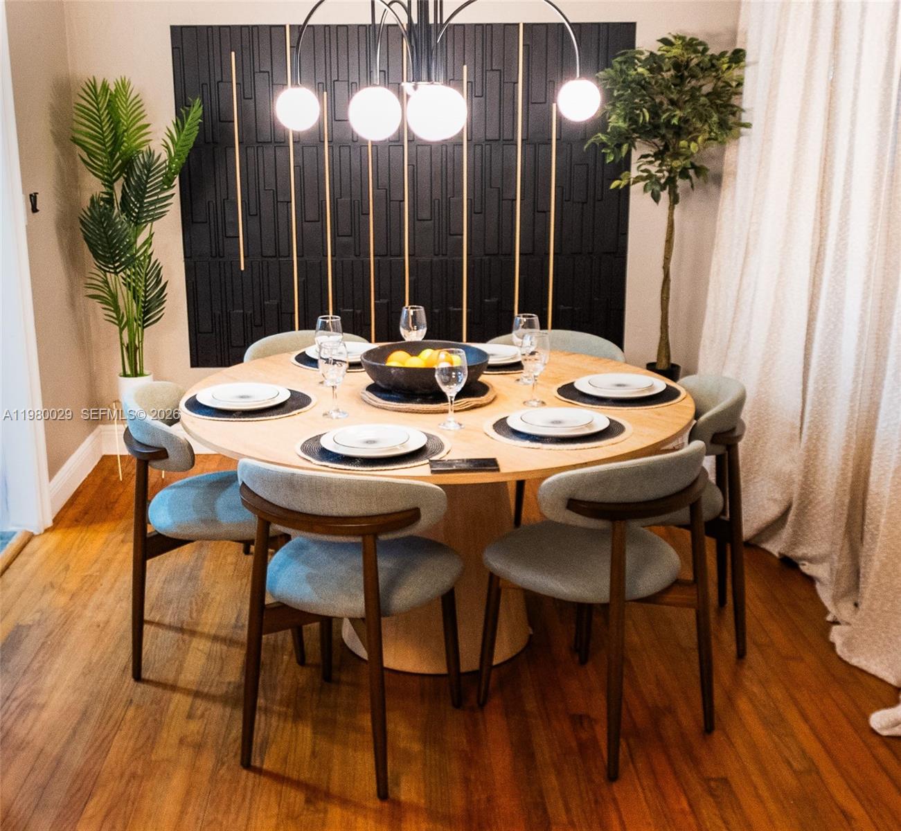 A round wooden dining table with six chairs sits in front of a black accent wall — 1419 N 16th Ct, Hollywood FL 33020, HOLLYWOOD, FL