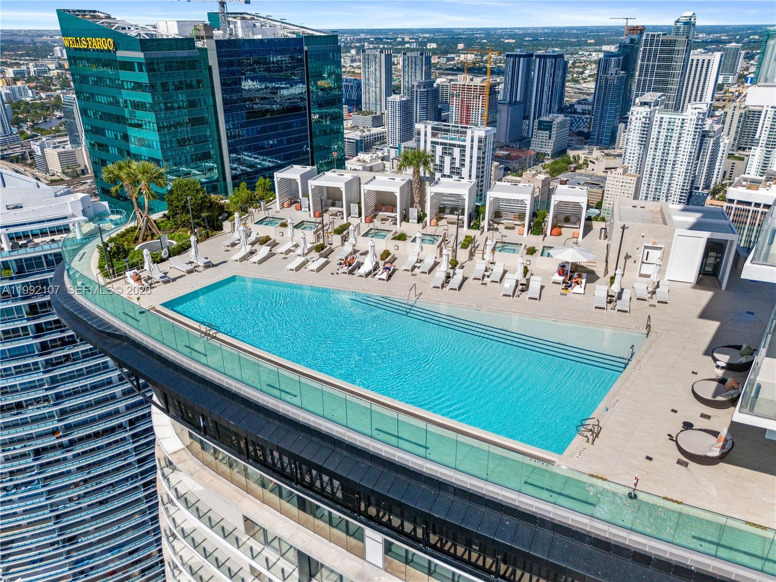 An elevated outdoor swimming pool deck features lounge chairs, cabanas, and city skyline views — 300 Biscayne Boulevard Way # 2103C, Miami FL 33131, MIAMI, FL
