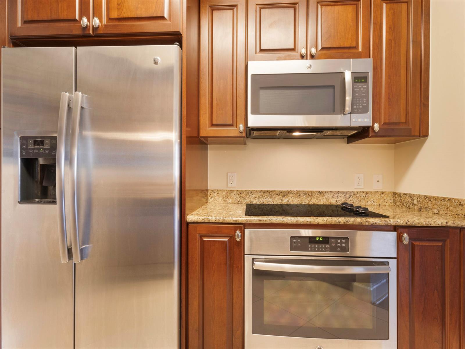 A kitchen features stainless steel appliances, wood cabinets, and granite countertops — 1690 Renaissance Commons Boulevard # 1412, Boynton Beach FL 33426, BOYNTON BEACH, FL
