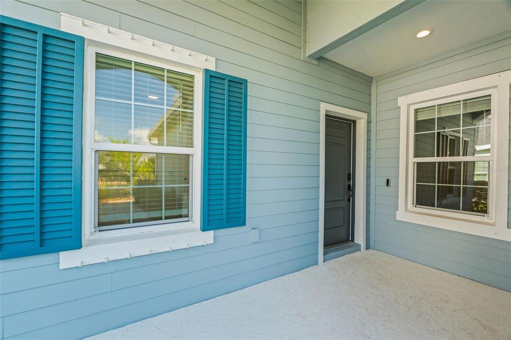 A light blue exterior wall features two windows with teal shutters and a dark door — 14632 BAREFOOT LANE, PARRISH, FL
