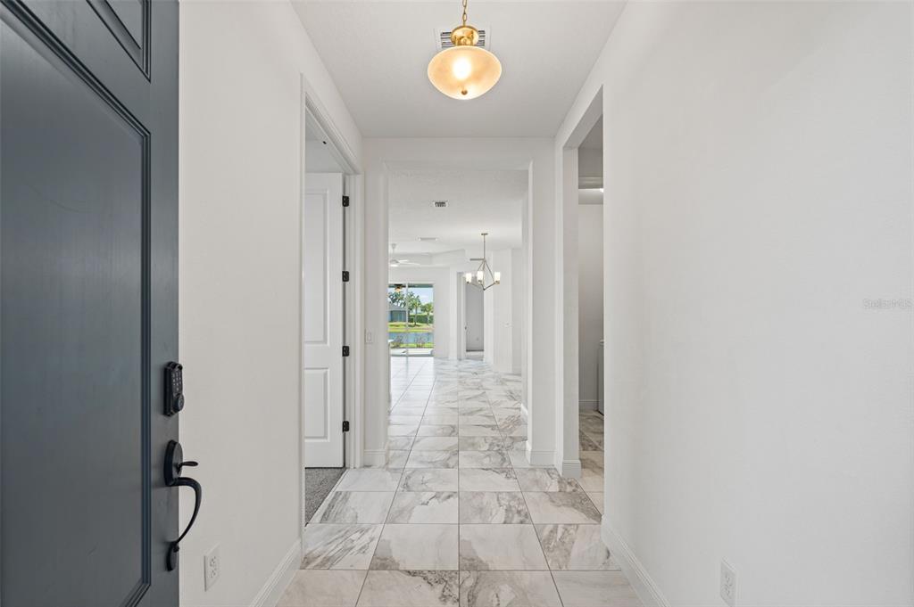 A bright entryway features white walls, marble-look tile flooring, and a view toward the backyard — 14632 BAREFOOT LANE, PARRISH, FL