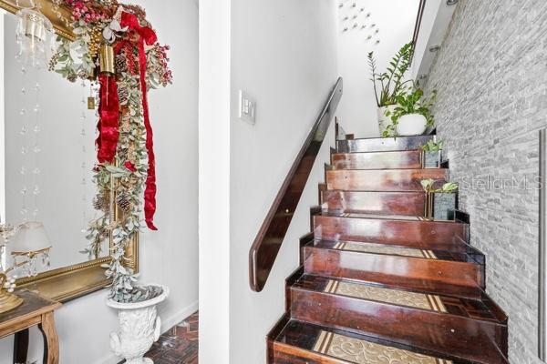 A staircase with dark wood treads and a stone-textured wall leads upward next to a mirror — #9 MANUEL POLOP SOLER, UTUADO, PR