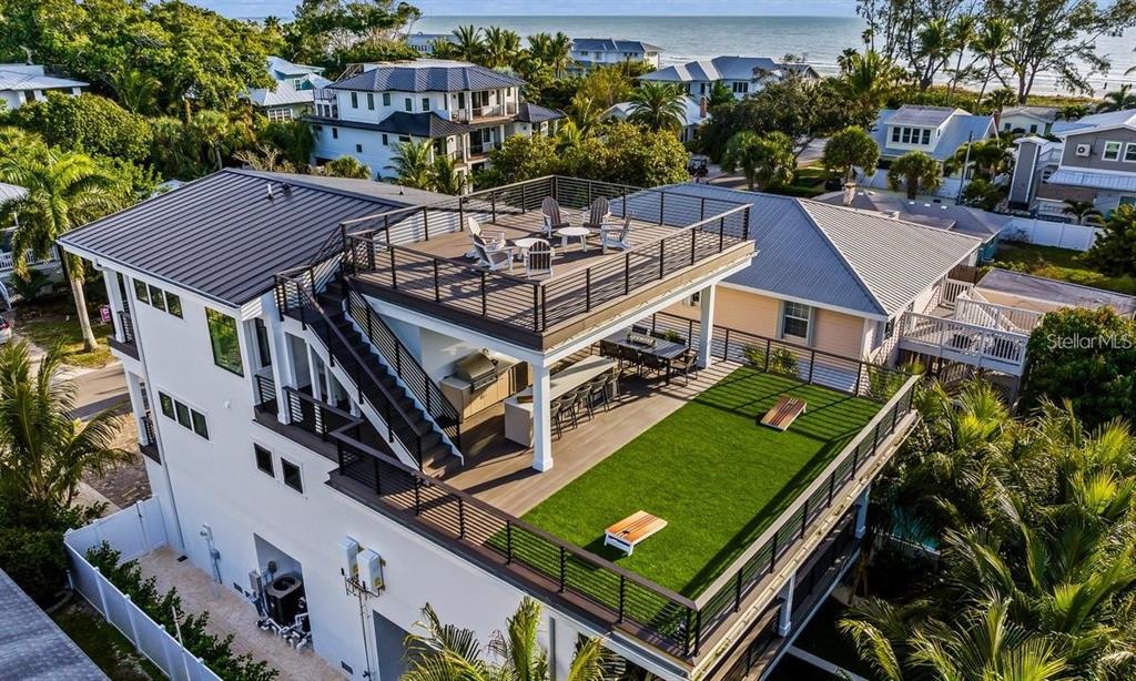 An elevated deck features a rooftop lounge, outdoor kitchen, dining area, and artificial turf lawn — 112 MAPLE AVENUE, ANNA MARIA, FL