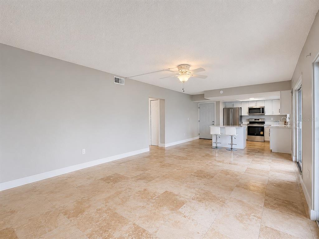 A neutral-toned bedroom features a queen bed, two nightstands, a ceiling fan, and tile flooring — 8818 BAY POINTE DRIVE UNIT 108, TAMPA, FL