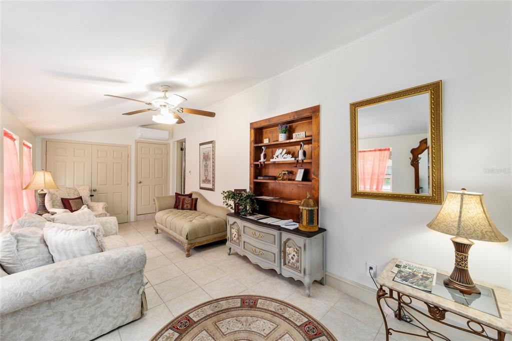 A living room features tile flooring, a ceiling fan, a wooden bookshelf, and a mirror — 20693 WALNUT STREET, DUNNELLON, FL