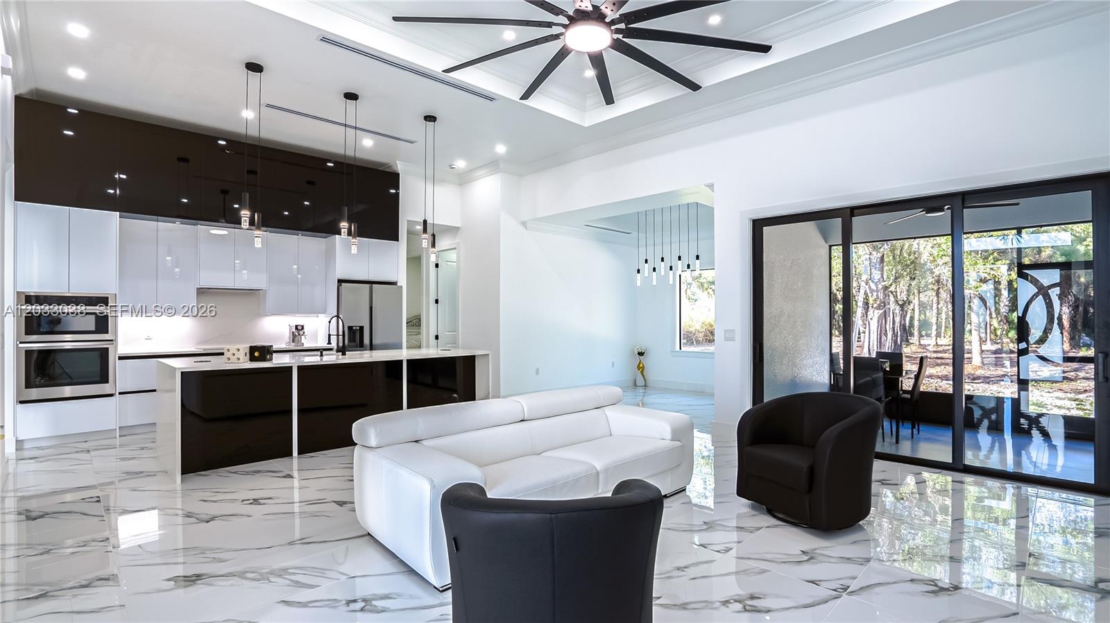 A modern open-concept kitchen and living area features white marble floors and dark cabinetry — 2565 28th Ave Se, Naples FL 34117, NAPLES, FL