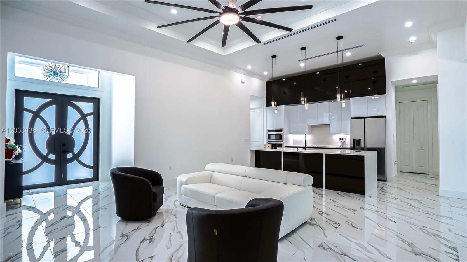 A modern open-concept living room and kitchen featuring white marble floors and high-contrast cabinetry — 2565 28th Ave Se, Naples FL 34117, NAPLES, FL