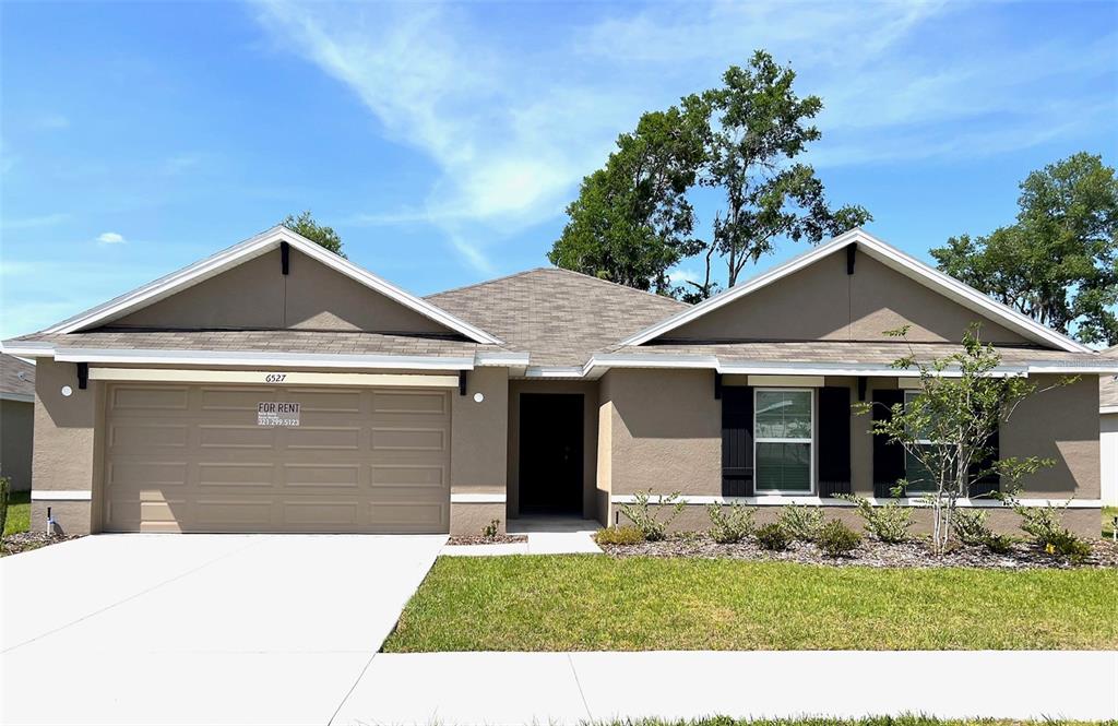 A single-story house with a tan stucco exterior, a two-car garage, and a shingled roof — 6527 SE 1ST LOOP, OCALA, FL