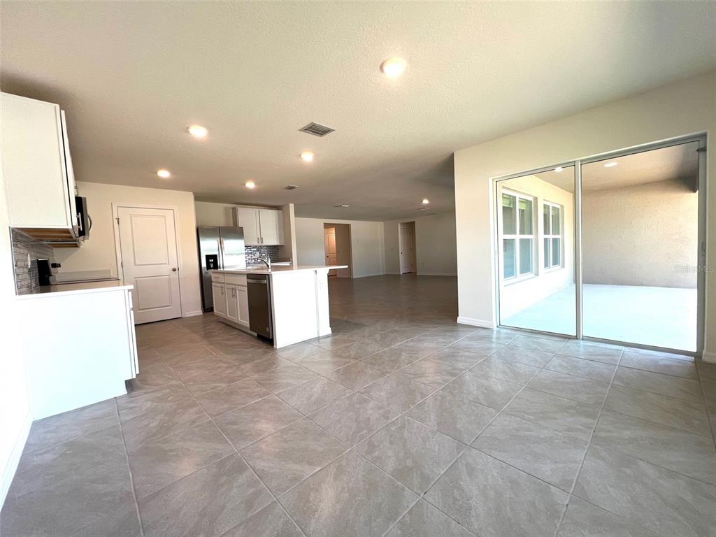 A kitchen with white cabinets and a center island opens into a large living area — 6527 SE 1ST LOOP, OCALA, FL