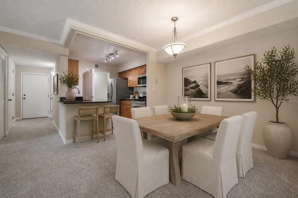A dining area with a wooden table and chairs sits adjacent to a kitchen with bar seating — 3274 HAVILAND COURT UNIT 101, PALM HARBOR, FL