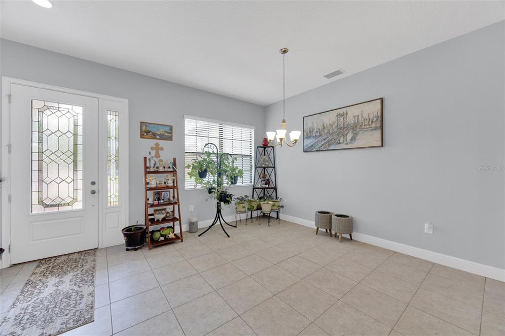 A dining area features light gray walls, tile flooring, a chandelier, and a front door — 11026 BRAHMAN RANCH CIRCLE, RIVERVIEW, FL