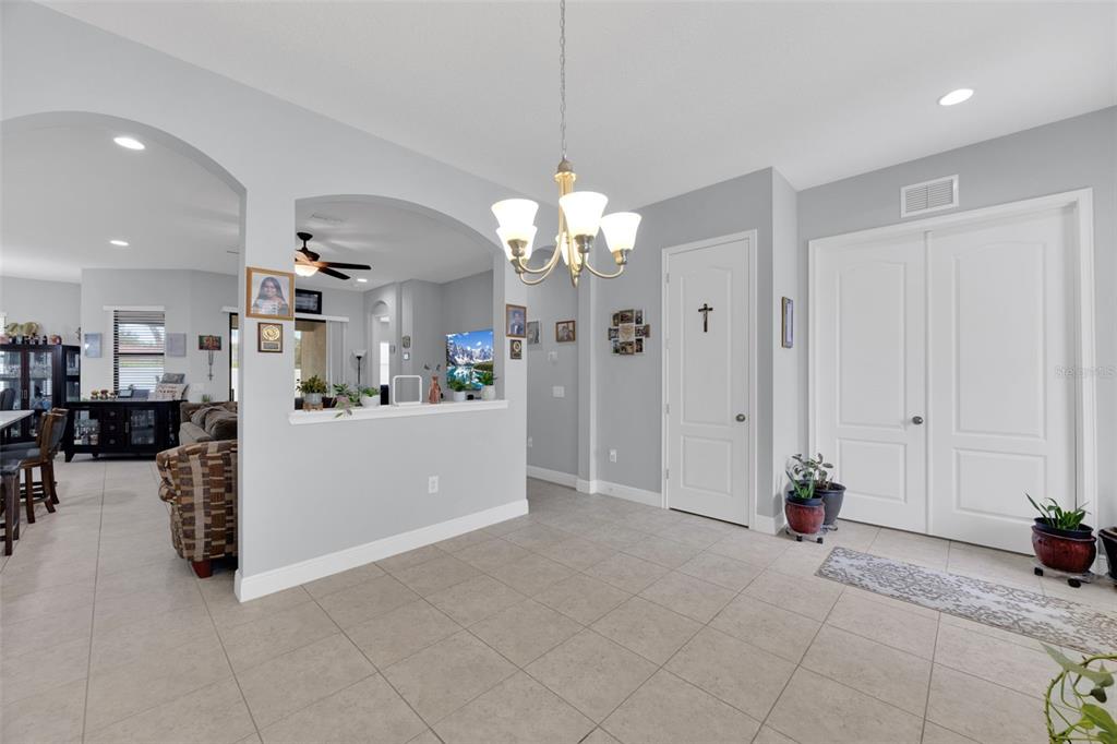 A bright foyer with tile flooring, a chandelier, and double doors leading to the entrance — 11026 BRAHMAN RANCH CIRCLE, RIVERVIEW, FL