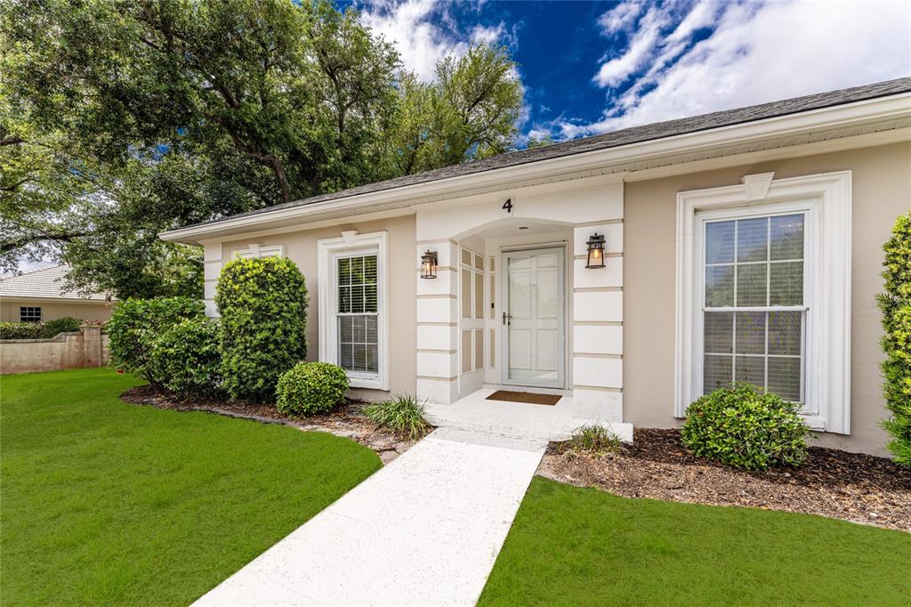 The exterior of a single-story house features a white front door and a paved walkway — 4 CURACAO CIRCLE UNIT 40, ENGLEWOOD, FL