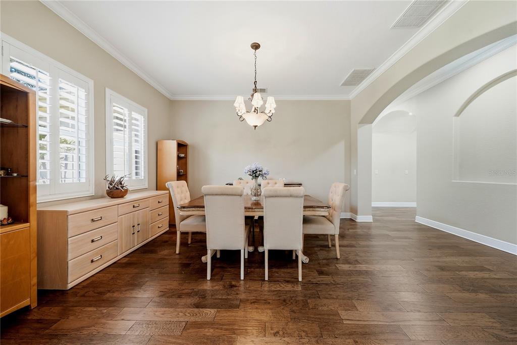 A dining room with a wooden table, upholstered chairs, a chandelier, and light wood cabinetry — 9244 RHEA DRIVE, ODESSA, FL