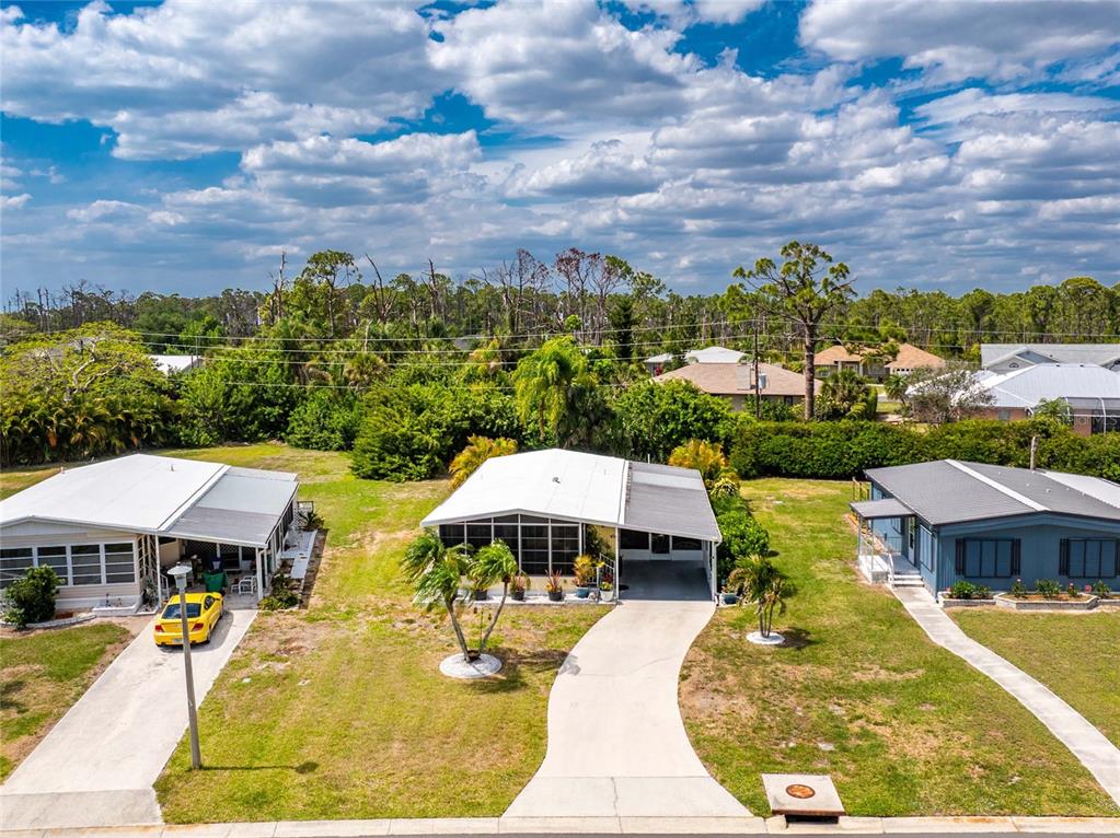 An aerial view shows three single-story houses with driveways and lawns under a cloudy sky — 3022 AUDUBON AVENUE, ENGLEWOOD, FL