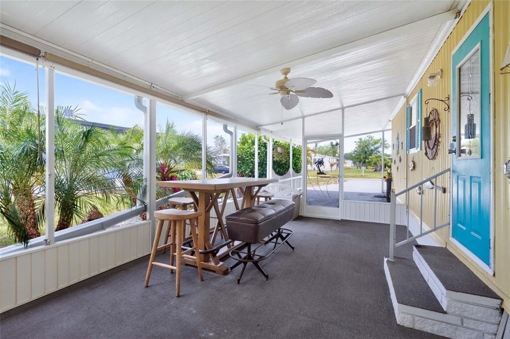 A screened-in porch features a high-top table with stools, a ceiling fan, and a blue door — 3022 AUDUBON AVENUE, ENGLEWOOD, FL