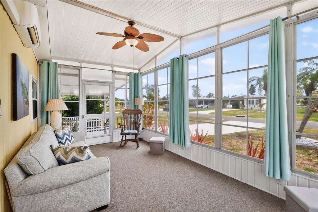 A sunroom features a gray sofa, a rocking chair, carpeted floors, and large screened windows — 3022 AUDUBON AVENUE, ENGLEWOOD, FL