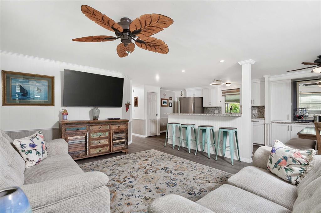 A living room with a palm-leaf ceiling fan, light gray sofas, and an open kitchen — 3022 AUDUBON AVENUE, ENGLEWOOD, FL