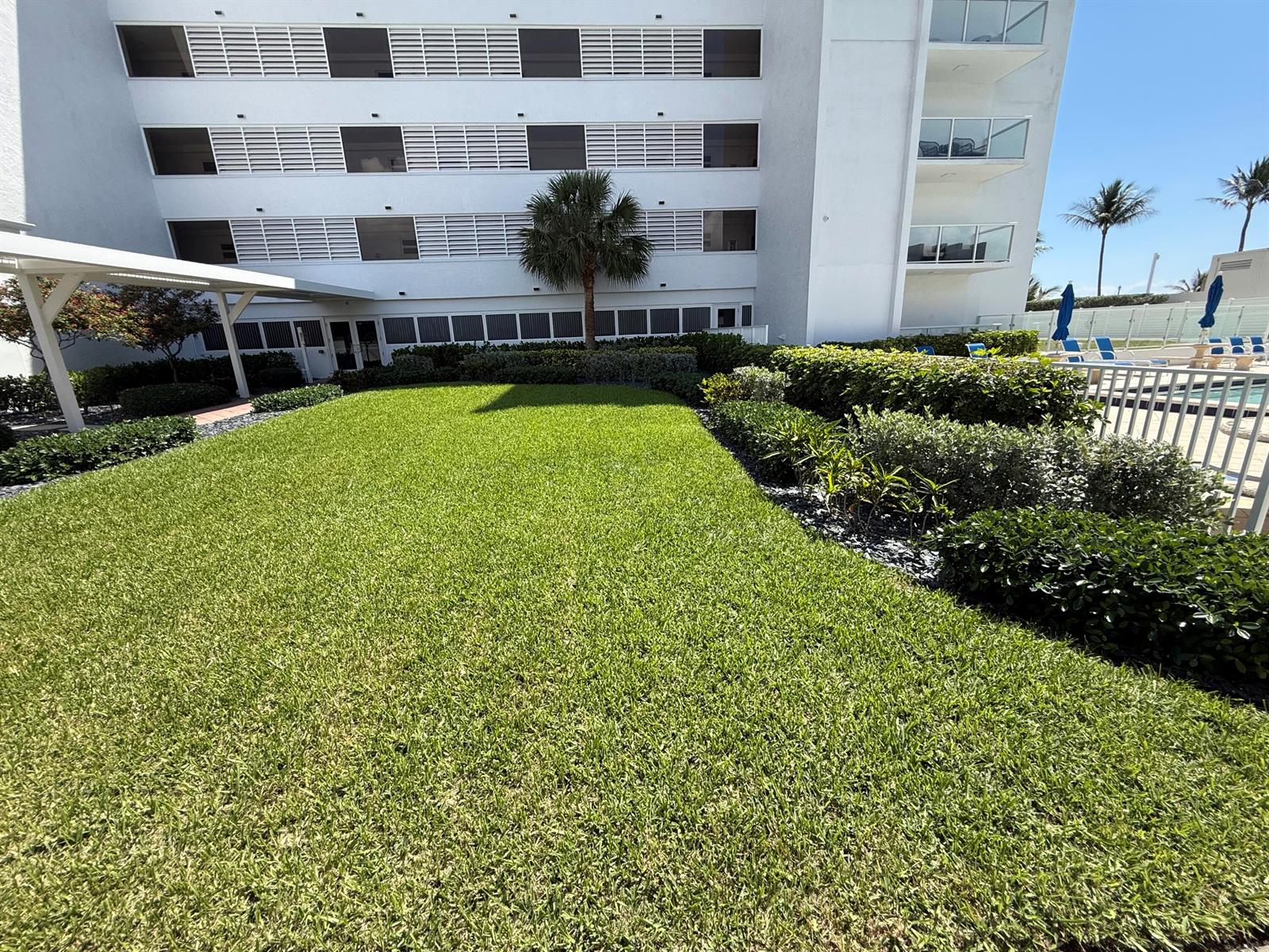 A grassy lawn sits in front of a multi-story white building with balconies — 2909 S Ocean Boulevard, Highland Beach FL 33487, HIGHLAND BEACH, FL