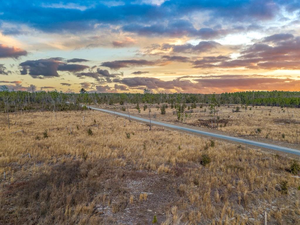 An aerial view of a paved road cutting through a flat, grassy, and sparsely wooded lot — TBD 211TH COURT, LIVE OAK, FL