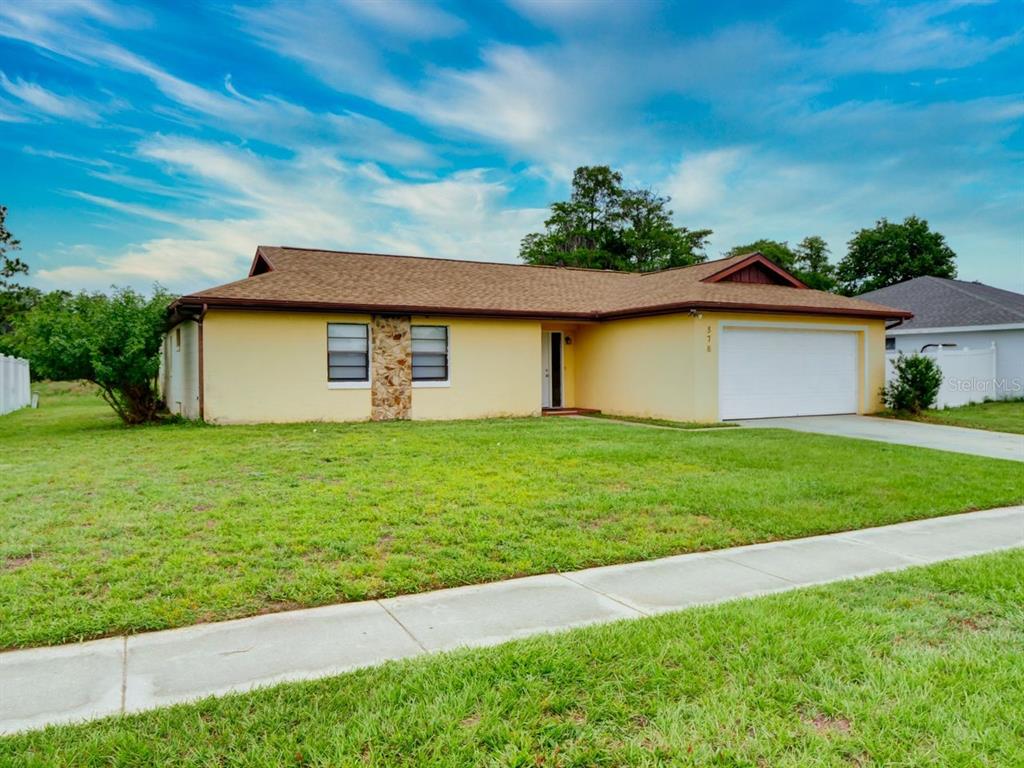 A single-story yellow house with a brown roof and a two-car garage — 378 BUTTONWOOD DRIVE, KISSIMMEE, FL
