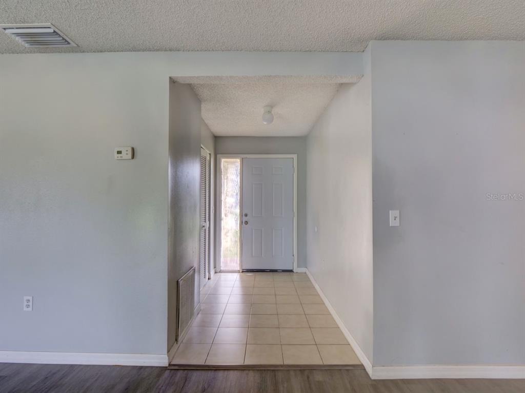 An entryway with a white front door, tiled floor, and a popcorn ceiling — 378 BUTTONWOOD DRIVE, KISSIMMEE, FL