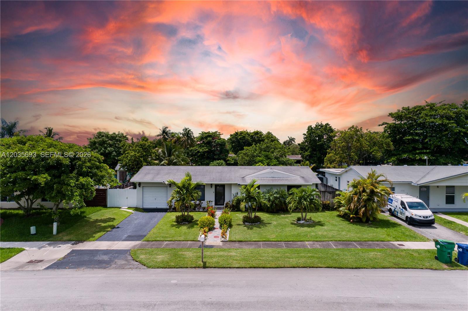 A single-story house with a white exterior, a garage, and a front lawn at sunset — 19311 Sterling Dr, Cutler Bay FL 33157, CUTLER BAY, FL