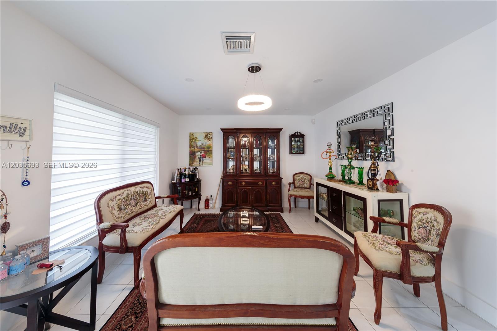 A formal living room features traditional wooden furniture, upholstered seating, and a large display cabinet — 19311 Sterling Dr, Cutler Bay FL 33157, CUTLER BAY, FL