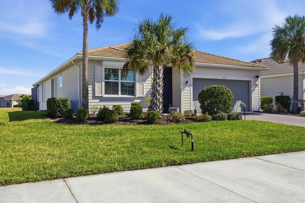 A single-story house with a tan exterior, a two-car garage, and palm trees in front — 15025 SPANISH POINT DRIVE, PORT CHARLOTTE, FL