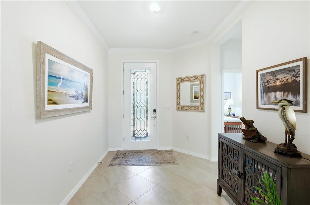 A bright entryway features a glass-paneled front door, tile flooring, and framed wall art — 15025 SPANISH POINT DRIVE, PORT CHARLOTTE, FL