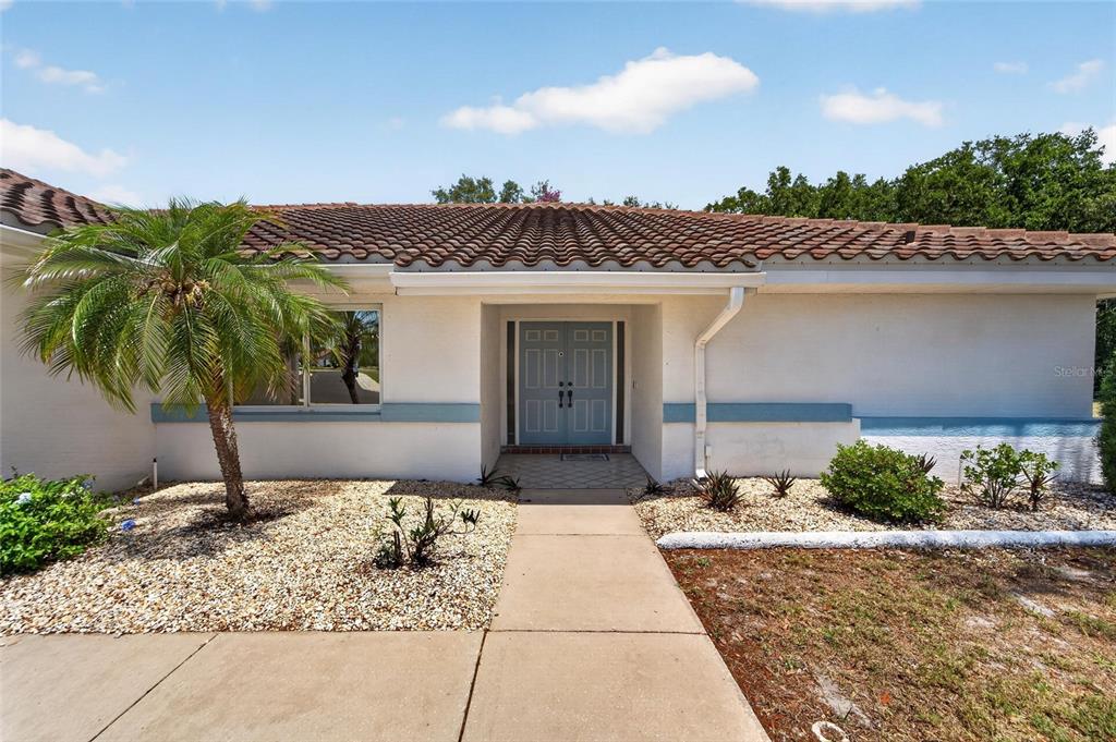 A single-story house with a tiled roof, white stucco walls, and a blue front door — 2015 BERRY ROBERTS DRIVE, SUN CITY CENTER, FL