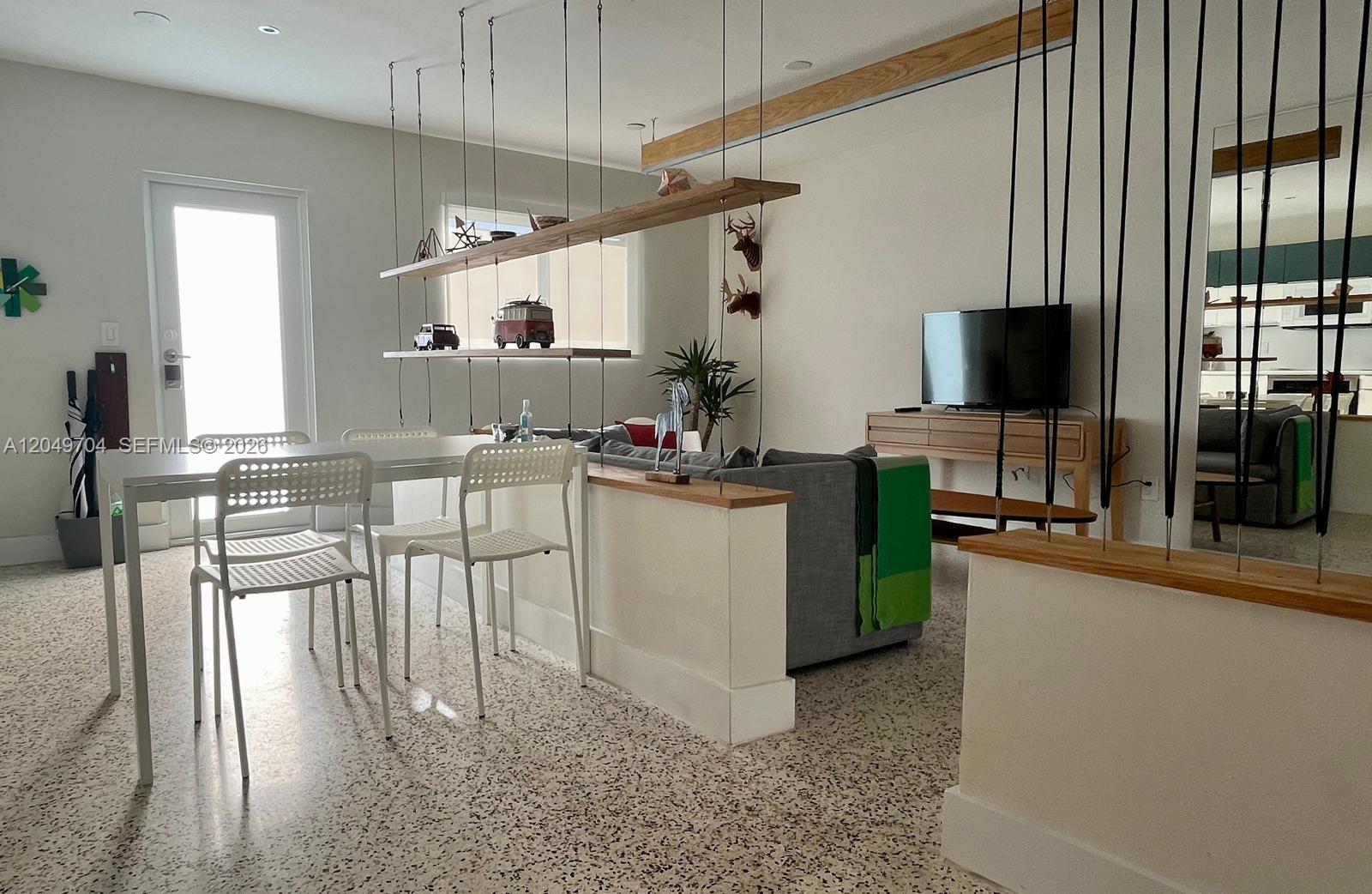 A living room and kitchen area feature a gray sofa, wooden coffee table, and terrazzo flooring — 451 SW 24th Rd # 2, Miami FL 33129, MIAMI, FL