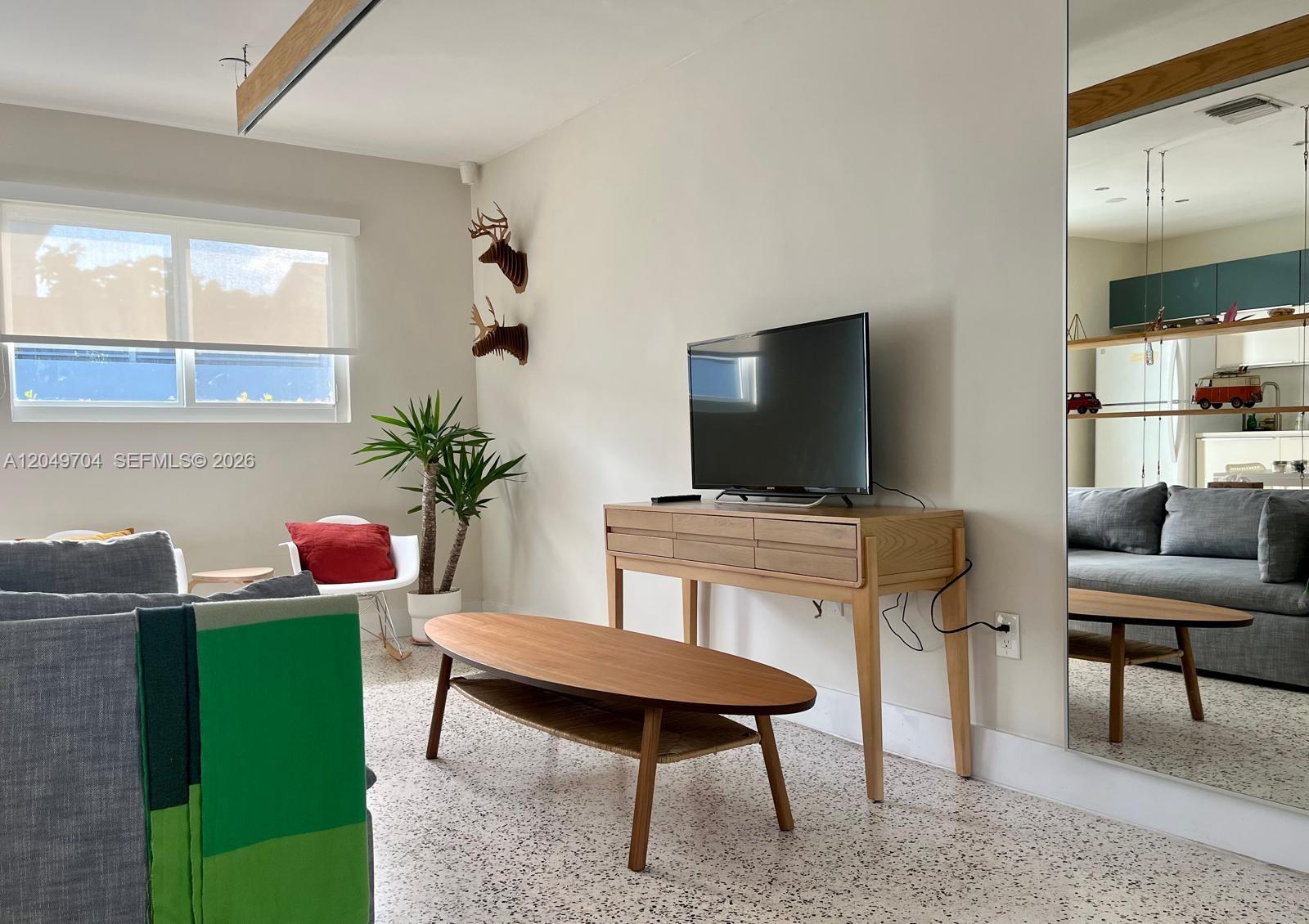 A dining area with a wooden table and chairs overlooks a living room with suspended shelving — 451 SW 24th Rd # 2, Miami FL 33129, MIAMI, FL