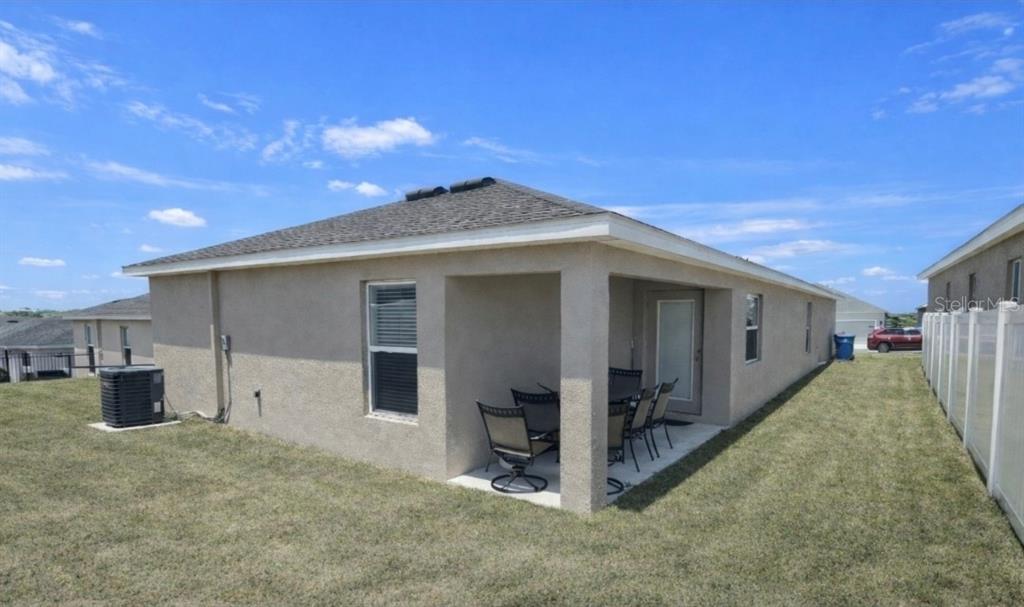 The exterior of a beige stucco house features a covered patio and a grassy yard — 1540 FLEUR DRIVE, DAVENPORT, FL