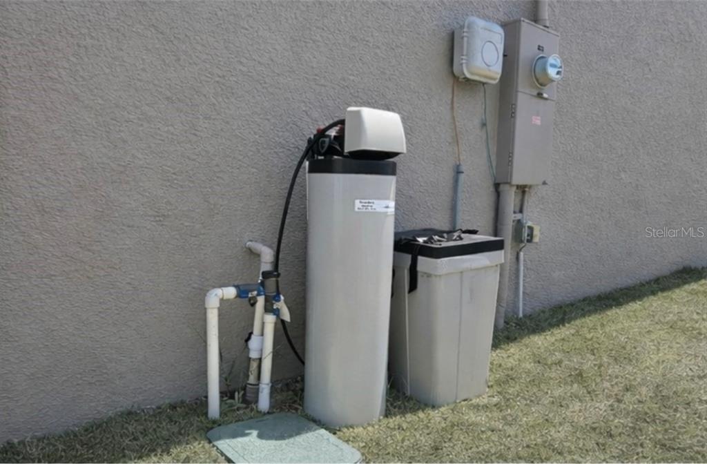 A water softener system and brine tank are installed against the exterior wall of a house — 1540 FLEUR DRIVE, DAVENPORT, FL