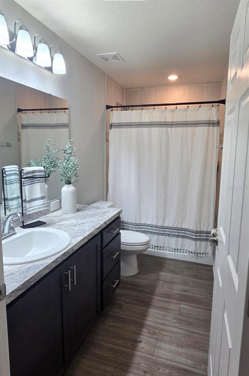 A bathroom features a dark vanity with a stone countertop, a toilet, and a shower curtain — 1540 FLEUR DRIVE, DAVENPORT, FL